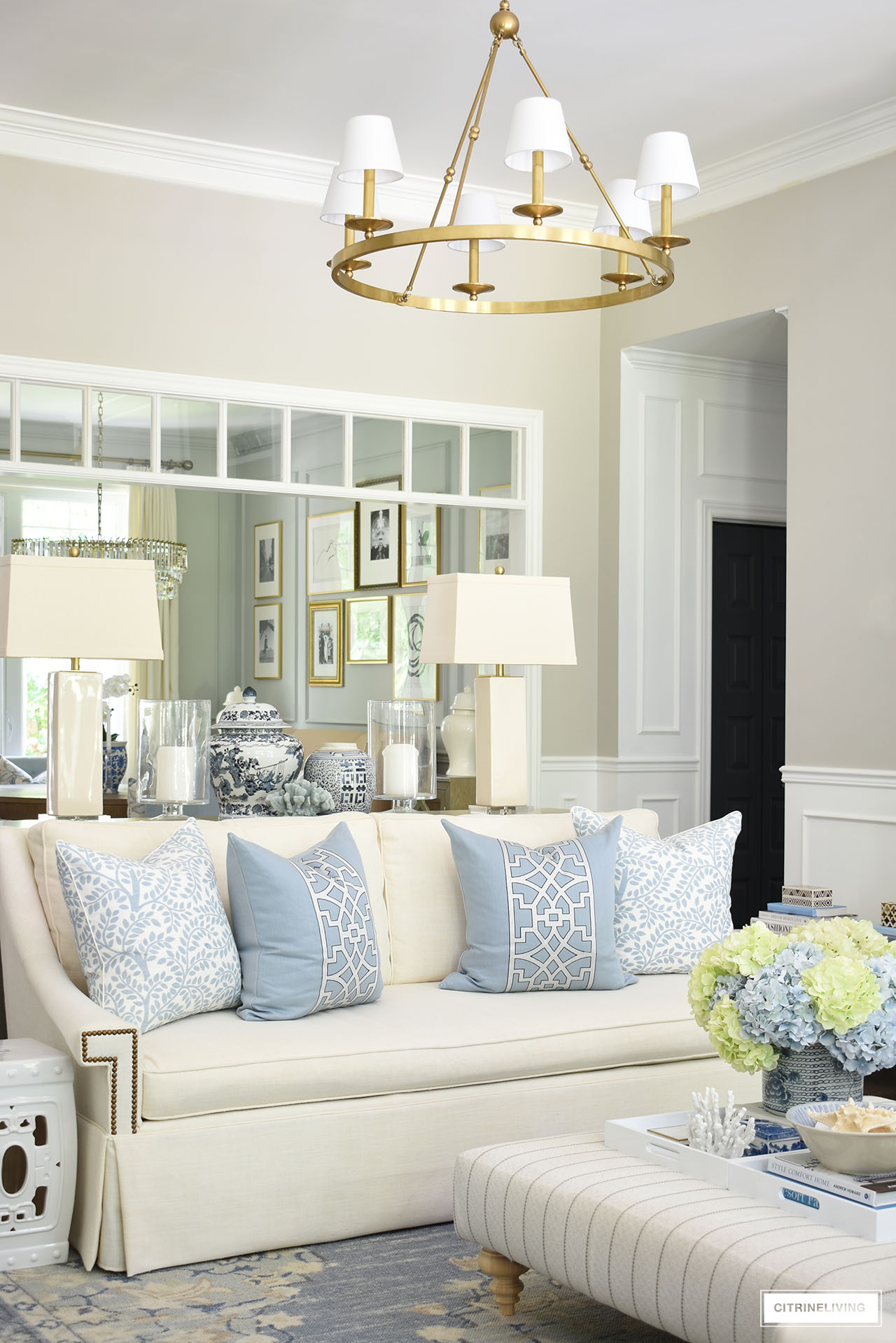 Living room styled with summer accents in light blue and white,  coastal accessories, designer pillows, ginger jars and hydrangeas.