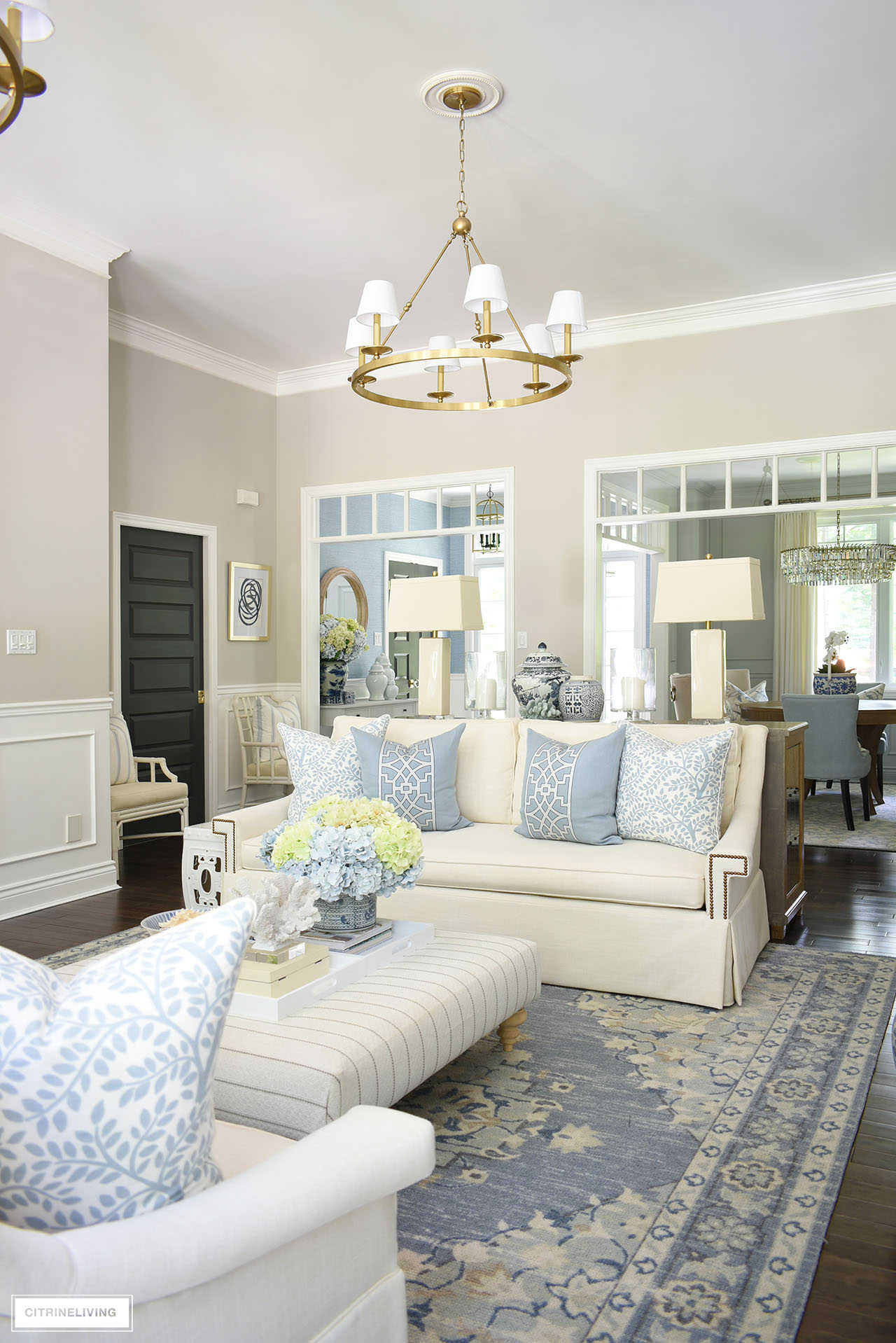 Chic summer living room decor featuring an elegant light blue and warm white color palette, blue and green hydrangeas and coastal accents.