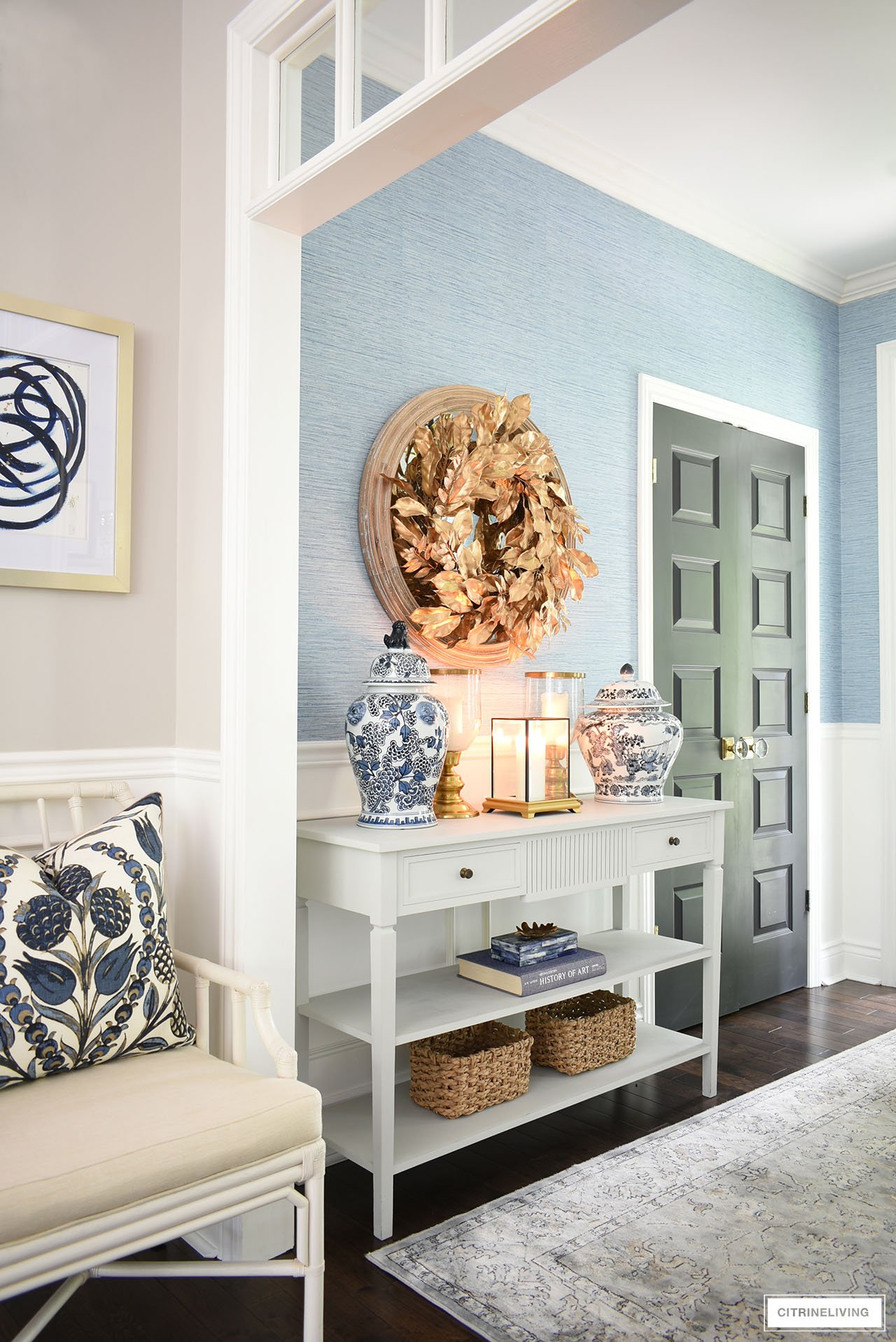 Entryway console table style for fall with a gorgeous gold wreath, ginger jars, gold candleholders and woven baskets.