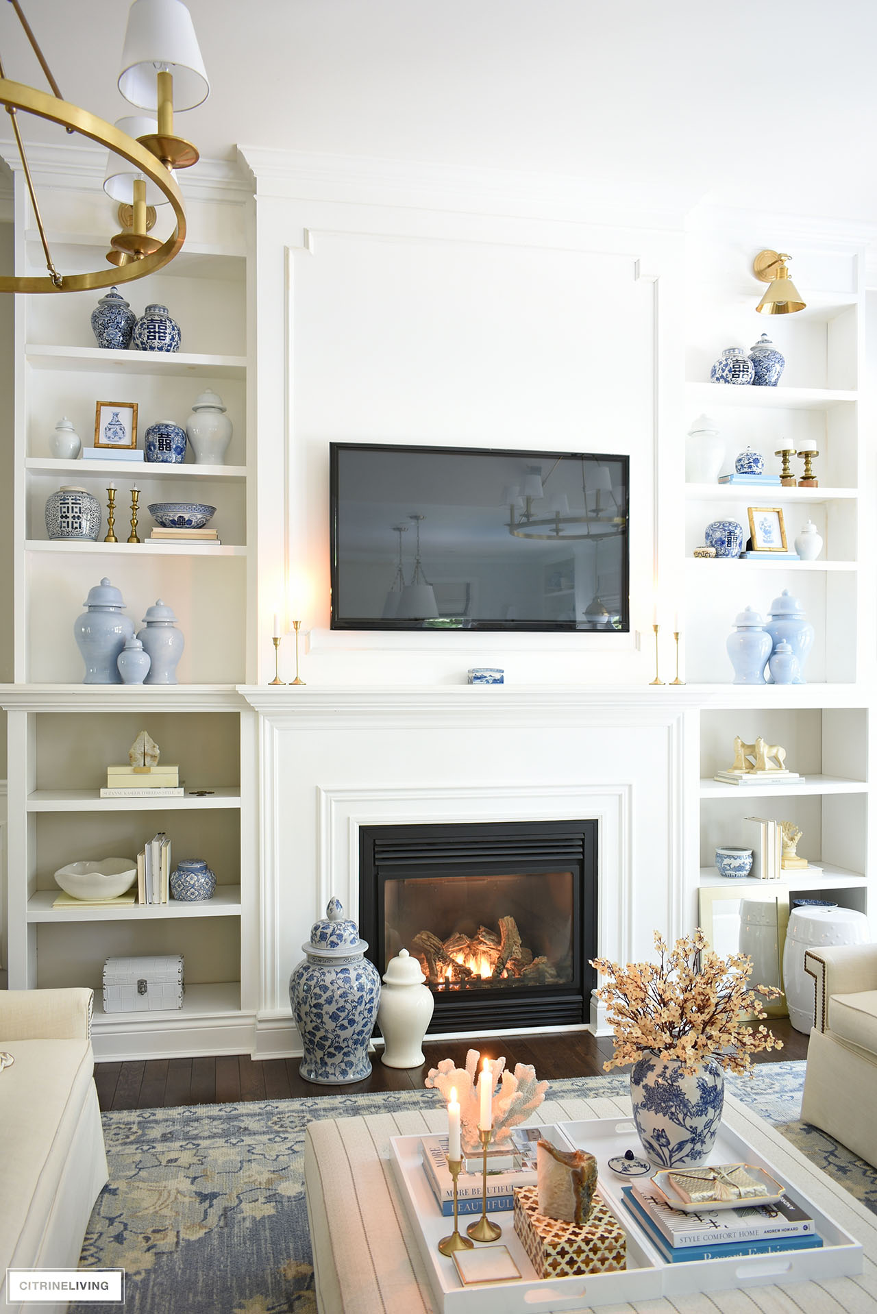 Beautiful tall bookshelves styled for fall in neutrals with touches of navy and white ginger jars, gold candlesticks and frames.