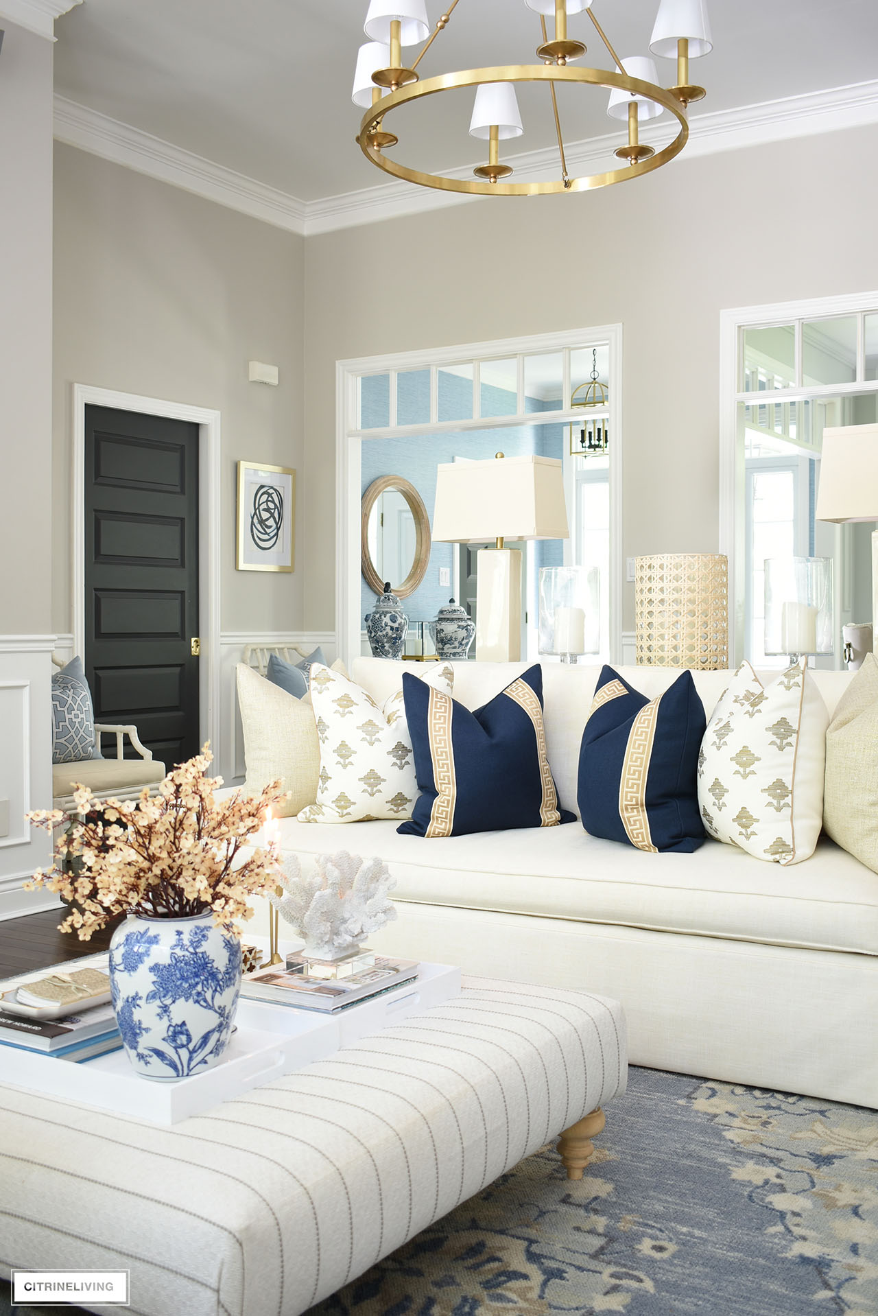 Neutral living room styled for fall with chic navy blue, tan ad gold pillows and accents.