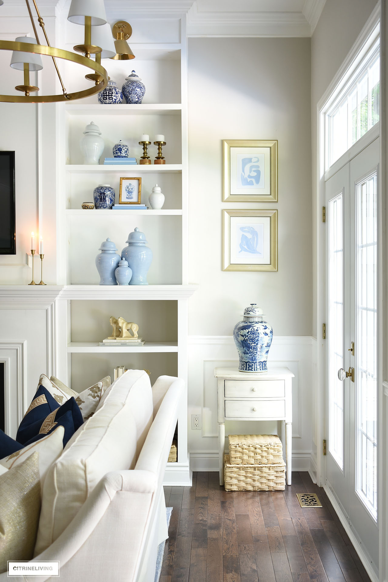 Bookshelves styled for fall with ginger jars, gold candlesticks and frames and color block books.
