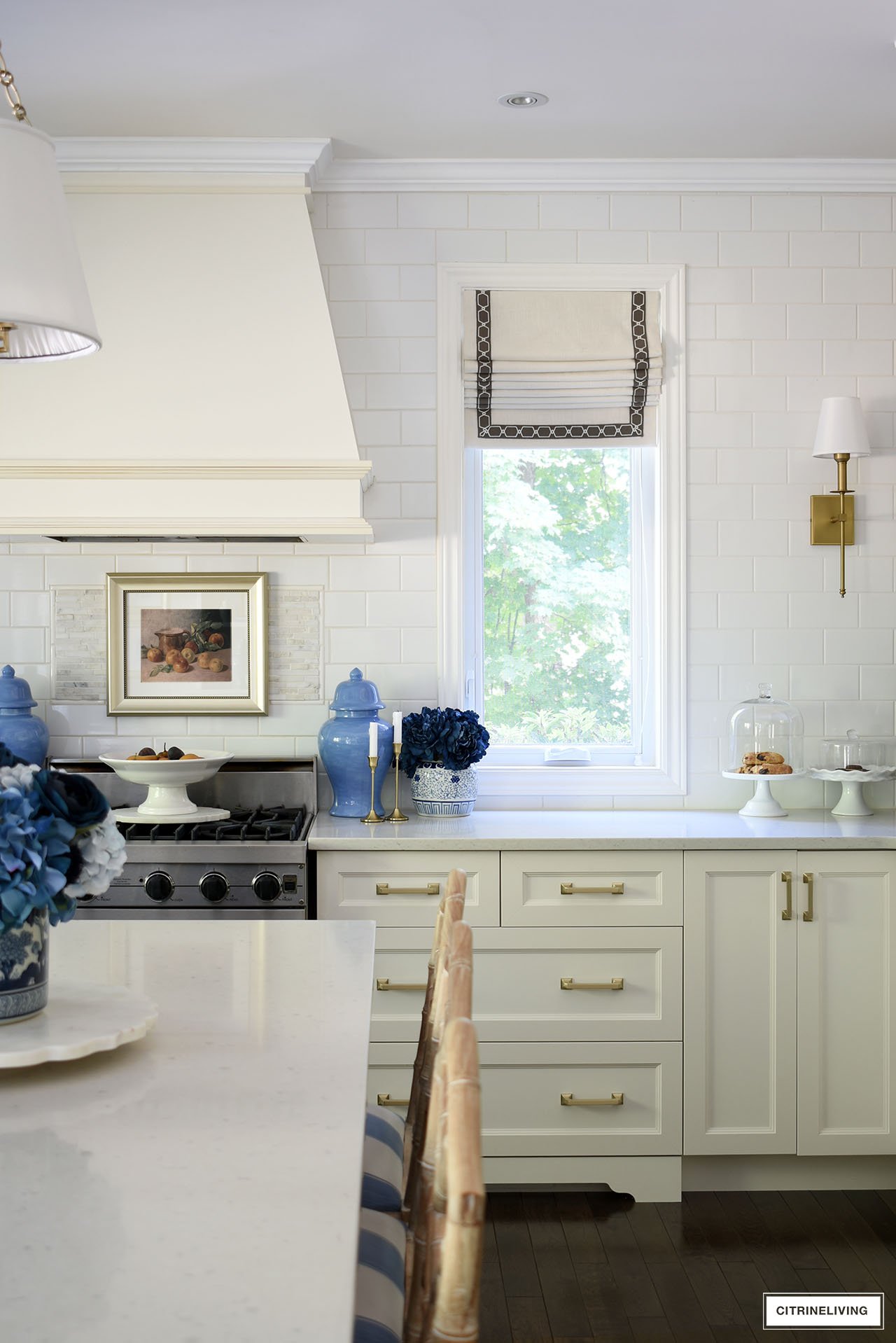 Kitchen decorated for fall using gold touches, navy blue flowers and vintage framed art.