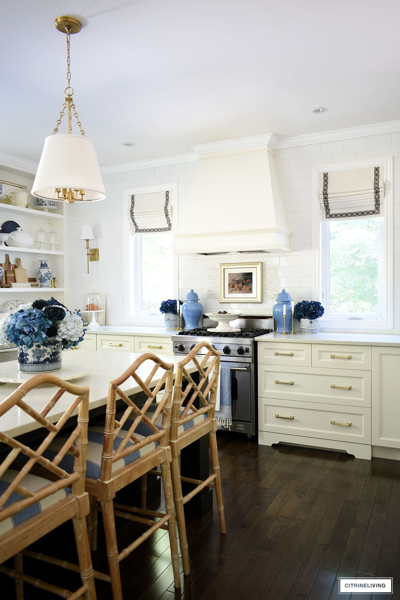 Elegant fall kitchen decor using vintage framed art, natural elements like fresh fruit and baked goods, blue floral arrangements and gold accents.