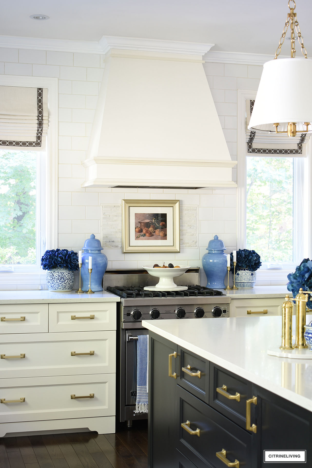 Kitchen stove decorated for fall with vintage art in a gold frame, blue ginger jars and navy blue flowers accented with gold touches is rich and sophisticated.