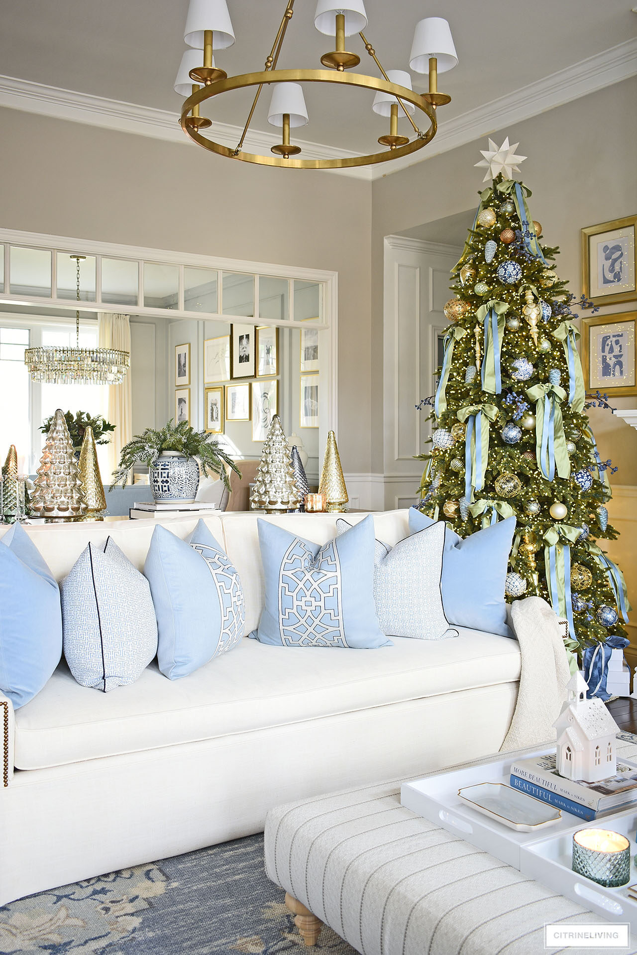 White sofa styled with blue pillows, a Christmas tree decorated with light green and light blue bows.