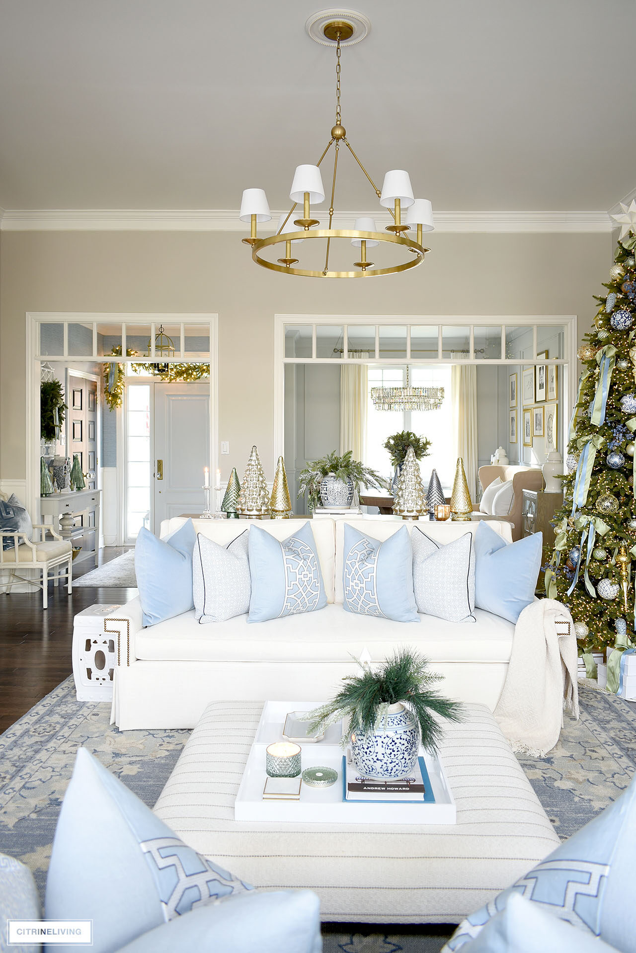 A Christmas decorated living room, a white sofa with blue and white pillows.