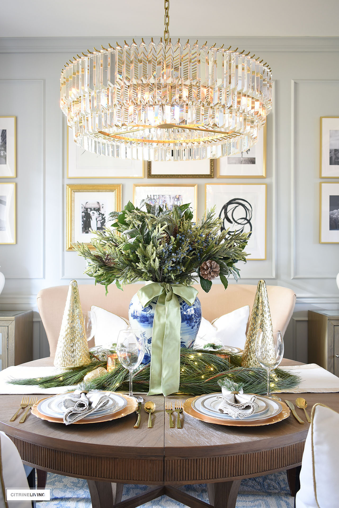 Dining room table set for Christmas with silver and gold dishes and holiday greenery