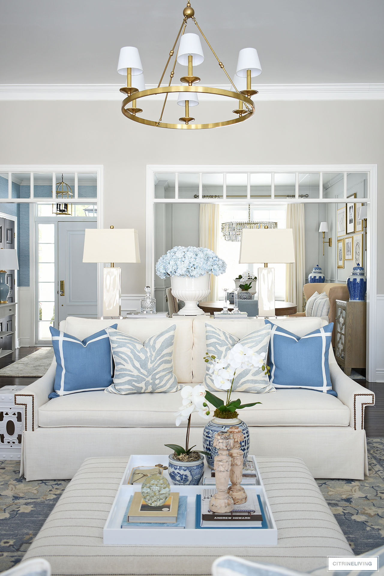 Living room decorated for spring with blue and white pillows - a muted zebra print and a vibrant solid blue with white topstitch ribbon detailing.