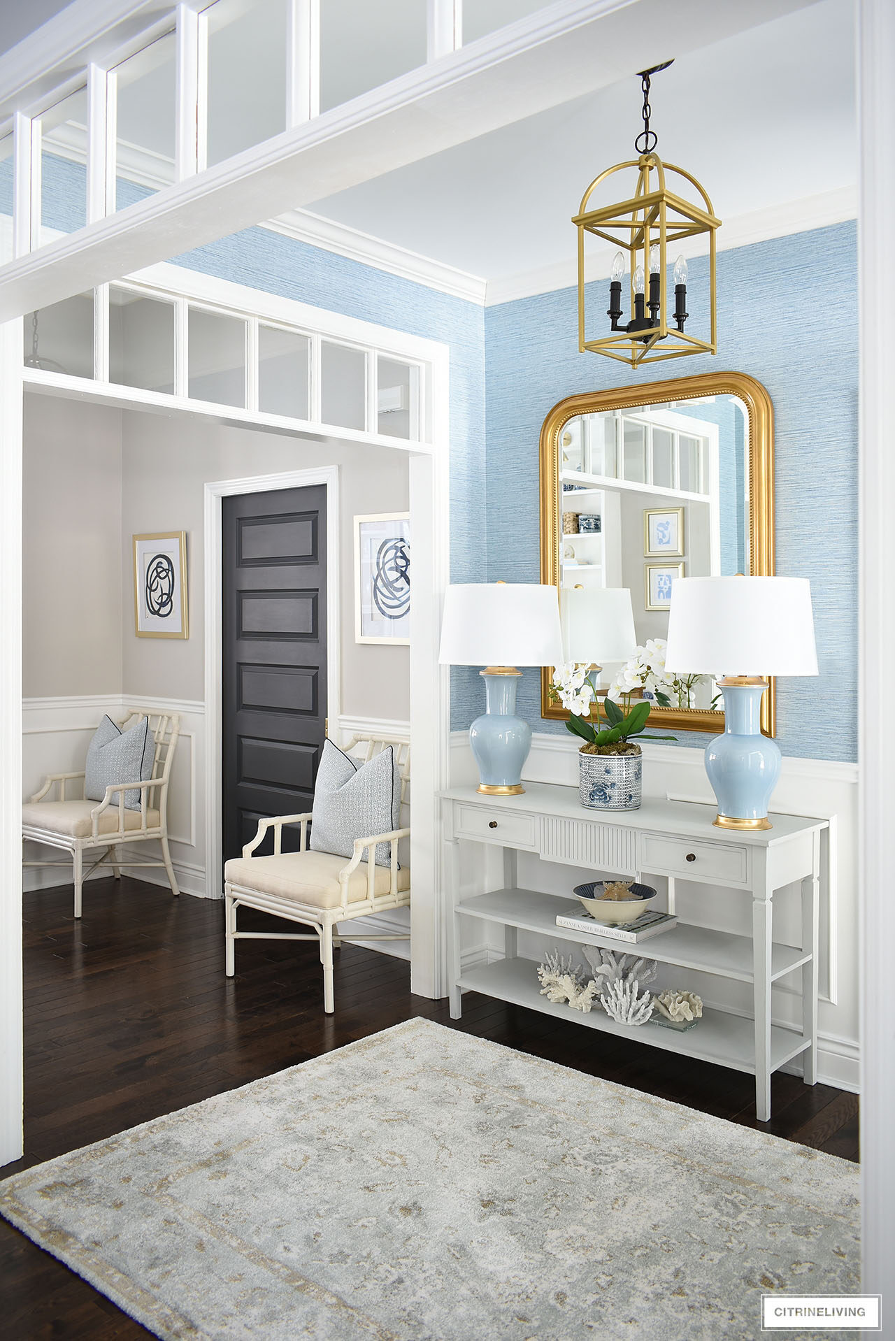Entryway decorated for spring featuring a pair of blue lamps, large gold statement mirror and a soft muted rug