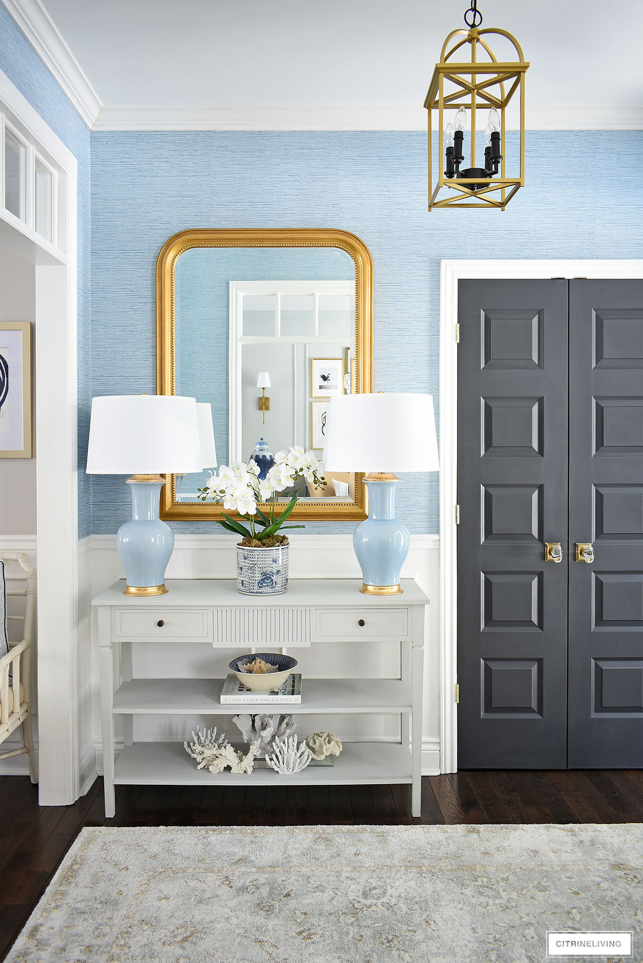 Elegant entryway with oversized gold arched mirror, a pair of blue and gold lamps
