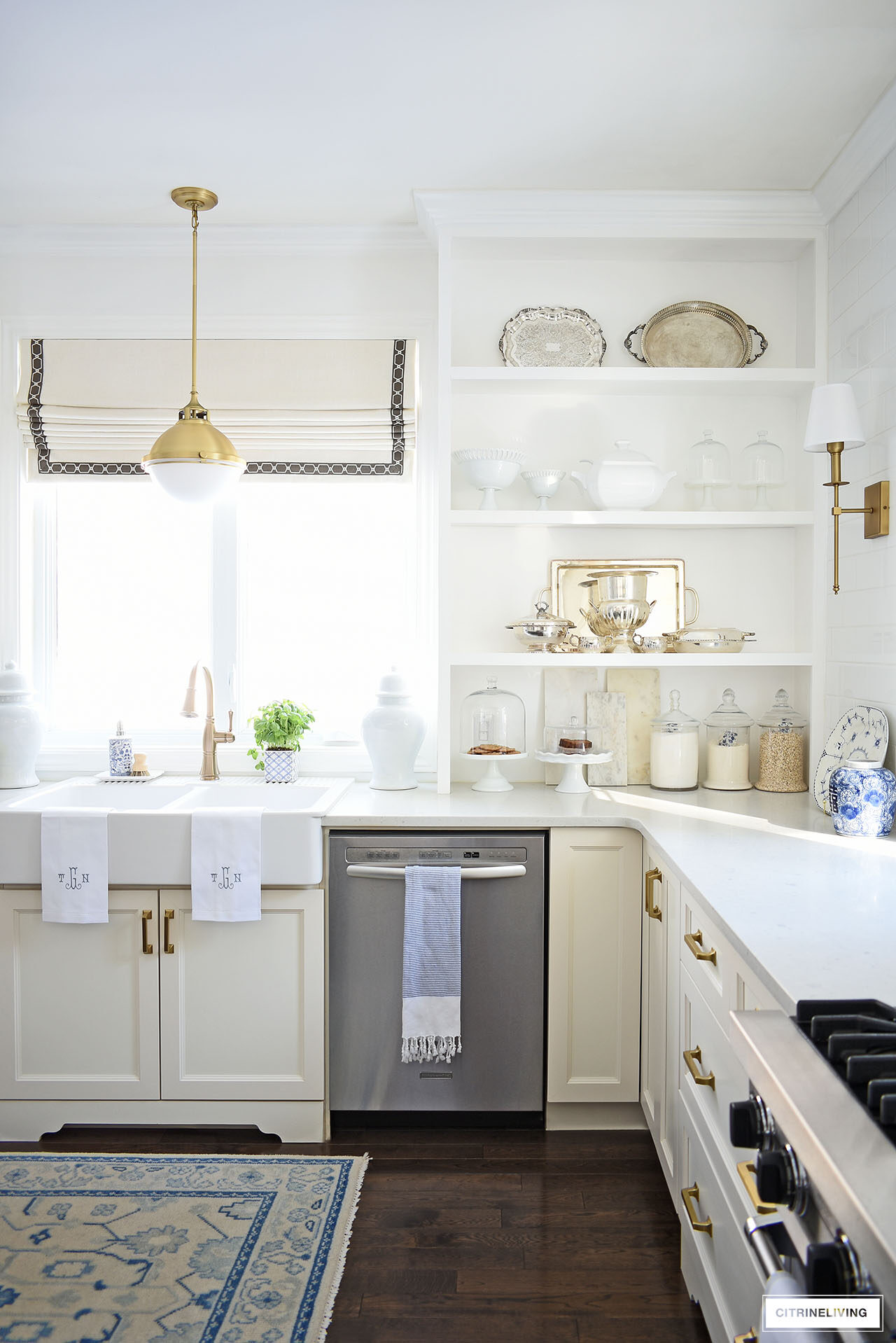 Traditional kitchen styled for spring with open shelves accessorized with silver serving pieces, white ceramics and glass apothecary canisters.