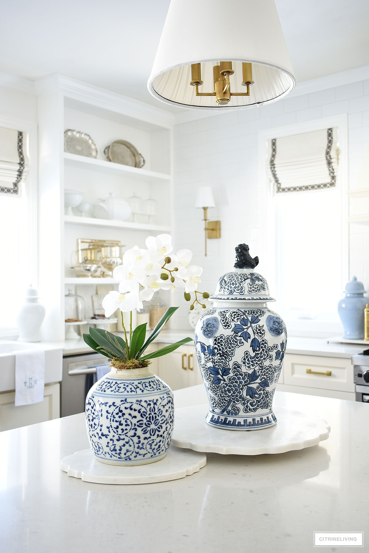 Kitchen island decorated for spring with blue and white ginger jars and an elegant orchid arrangement, set on marble boards.