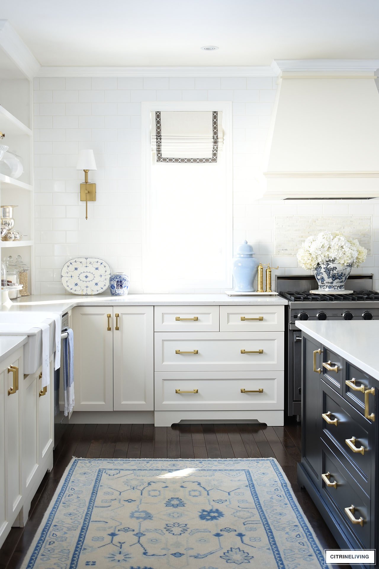 Elegant, classic white and black kitchen styled for spring with blue and white ginger jars, white orchids and hydrangeas.