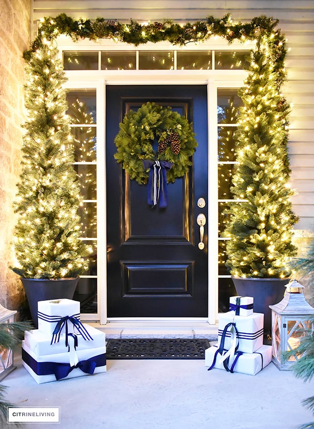 https://citrineliving.com/wp-content/uploads/2023/06/christmas-porch-with-white-presents-fresh-wreath-garland-and-pencil-trees-2.jpg