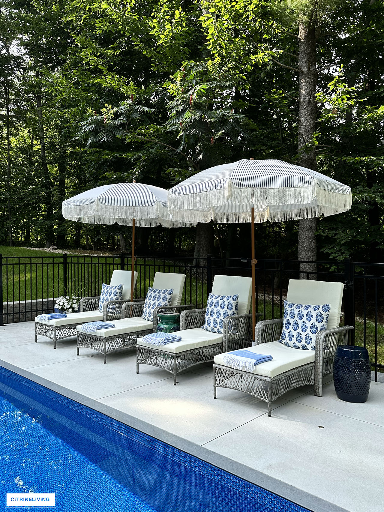 Resort style backyard with in ground pool, loungers, fringe umbrellas