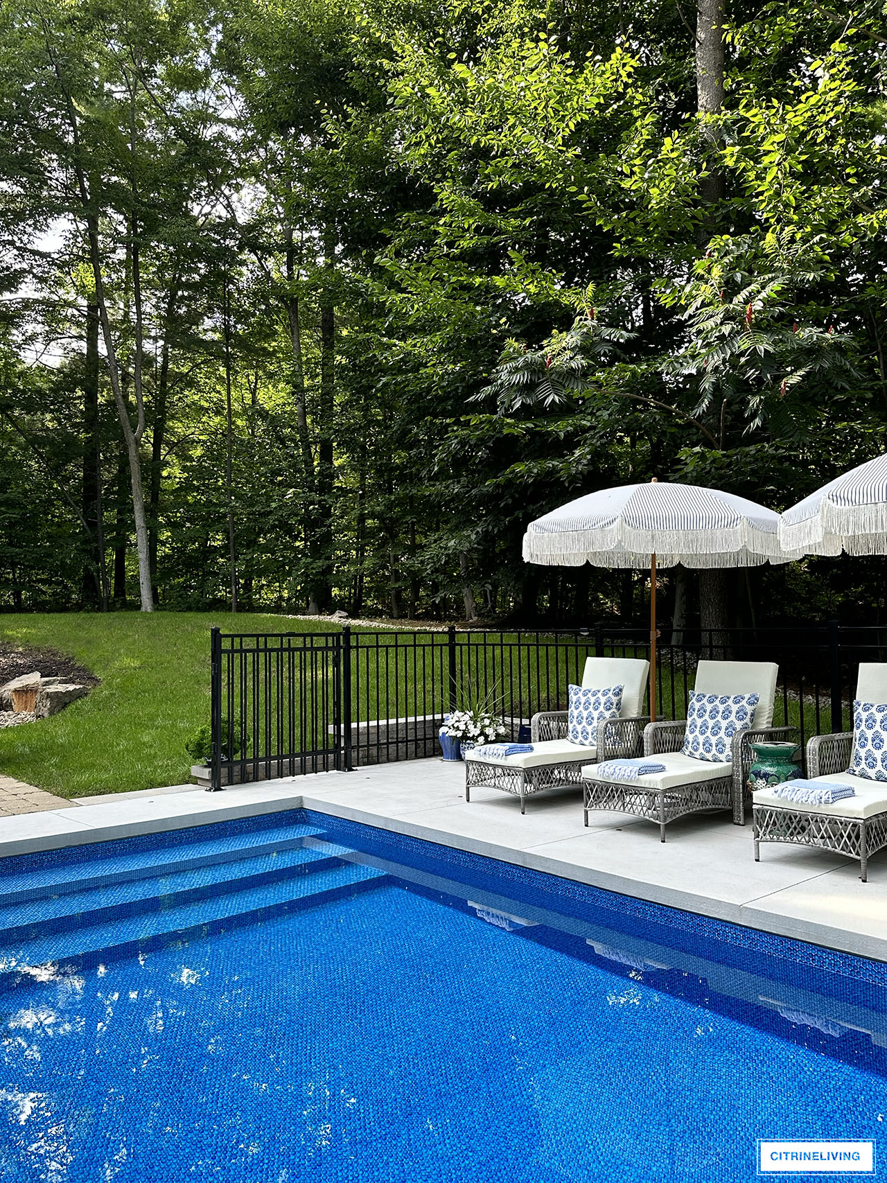 Resort style backyard with in ground pool, loungers, fringe umbrellas