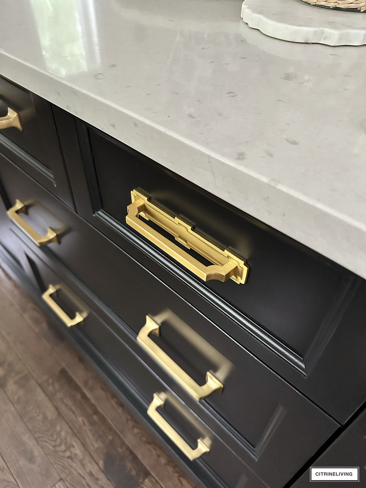 Brass drawer pull with backplate on black kitchen drawer
