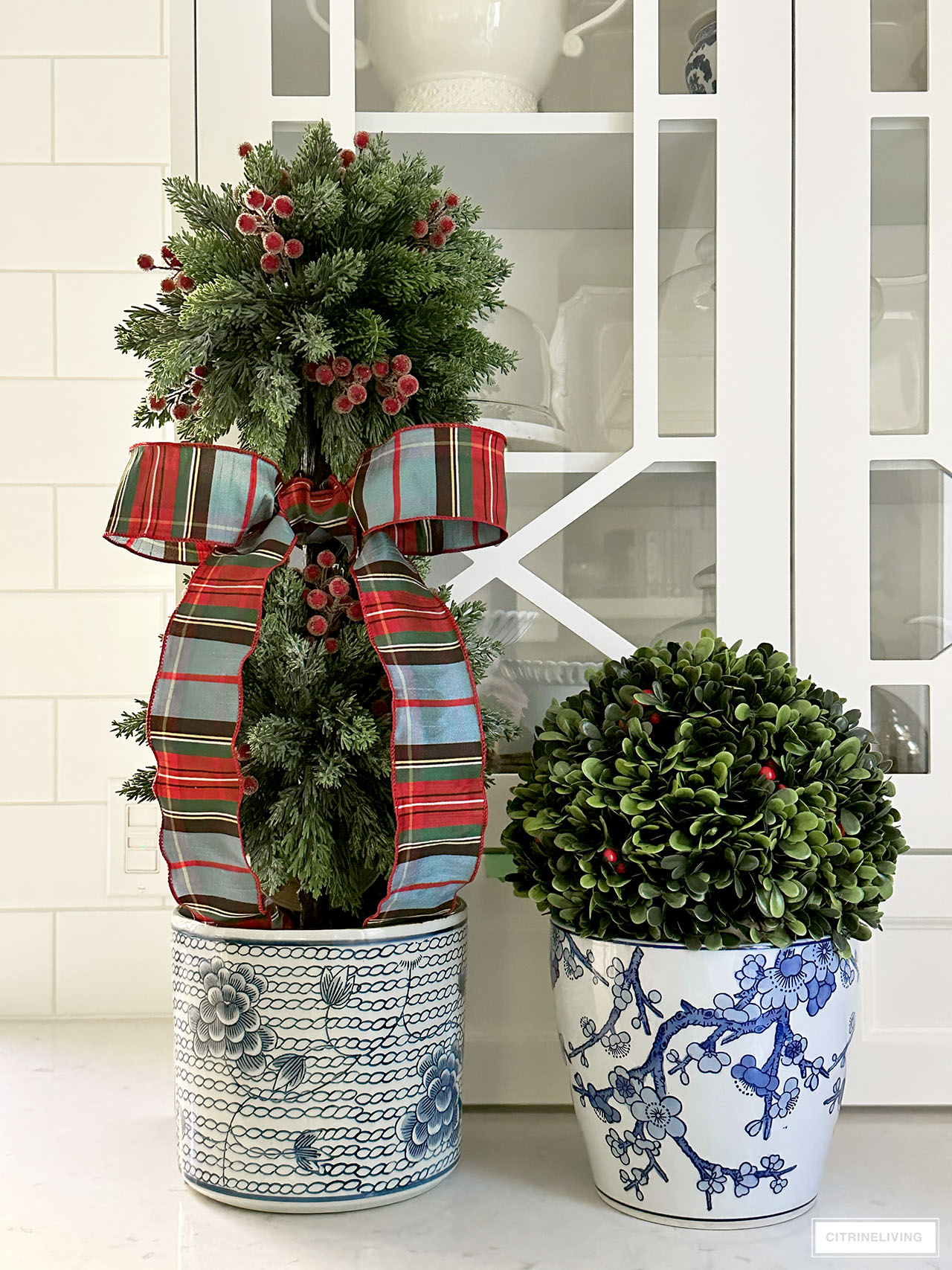 Christmas topiaries with red berries accented in plaid ribbon and chinoiserie planters