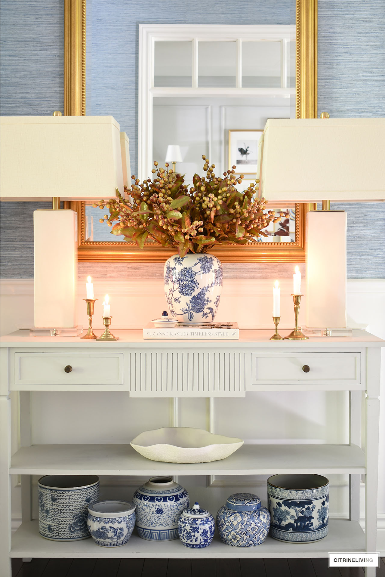 A decorated console table for fall with a beautiful berry and leaf arrangement.