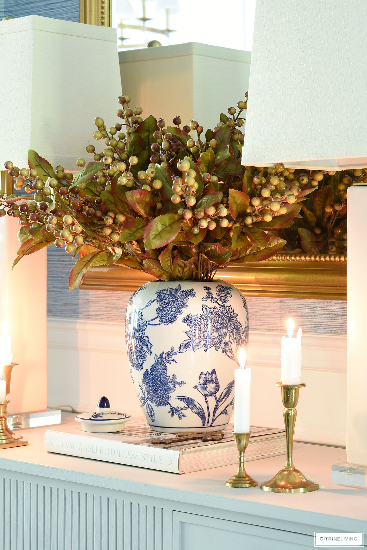 A blue and white jar with berries and leaves is a chic fall centerpiece.