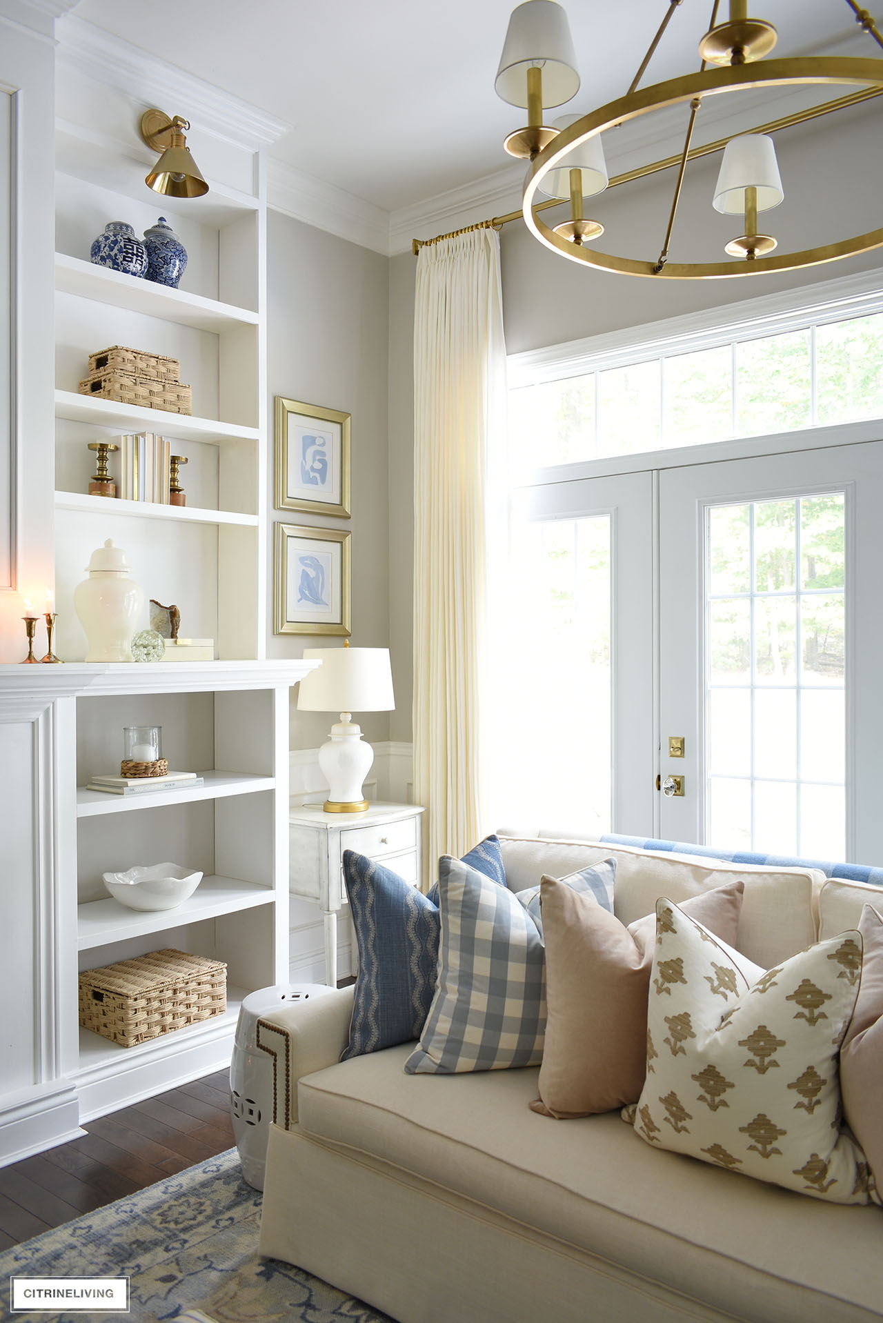 Living room corner with a white ginger jar lamp, bookshelves styled with simple decor