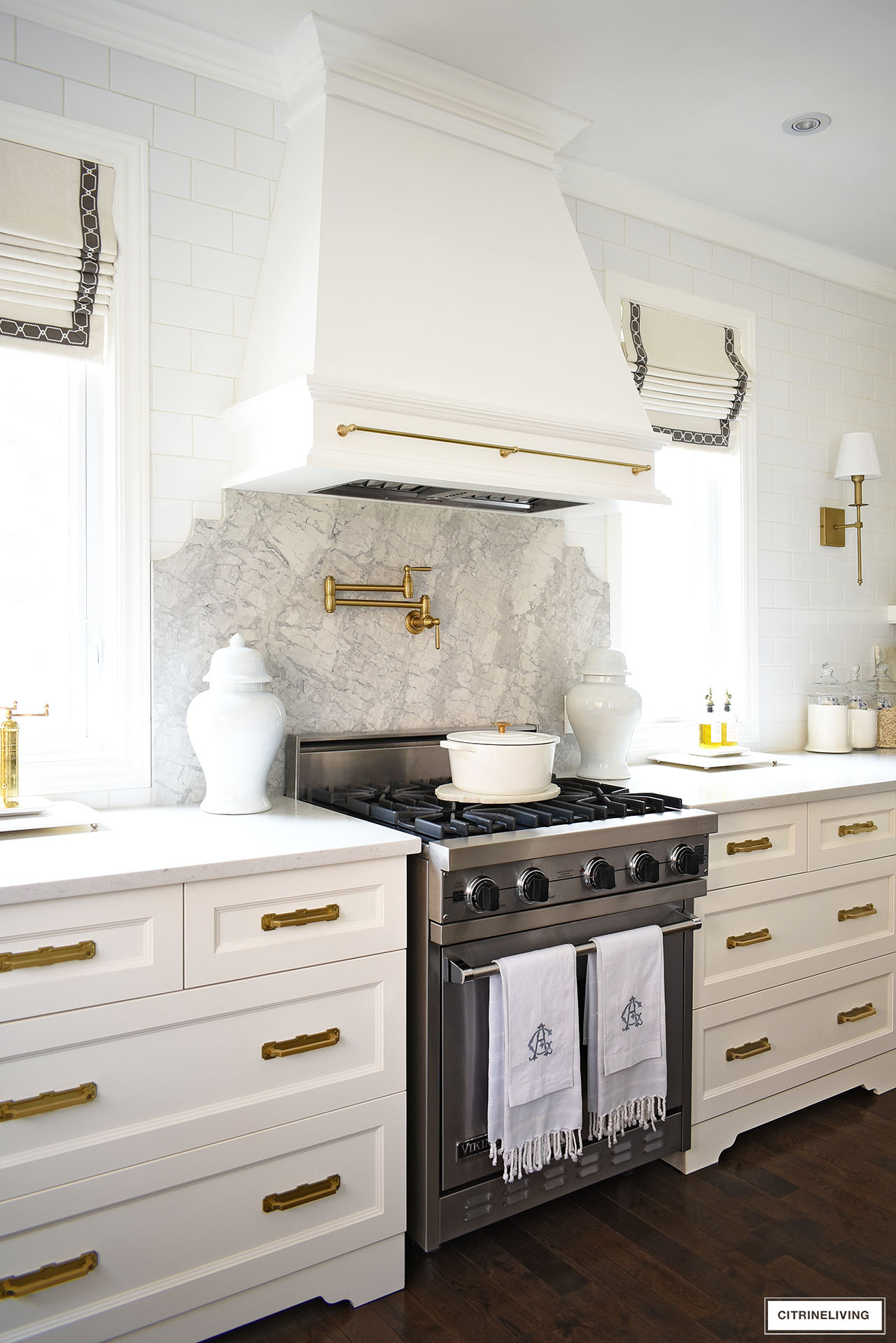 white kitchen with range hood with quartz backsplash