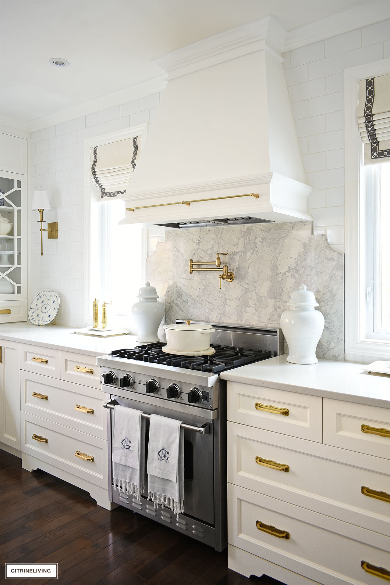 white kitchen with range hood with quartz backsplash