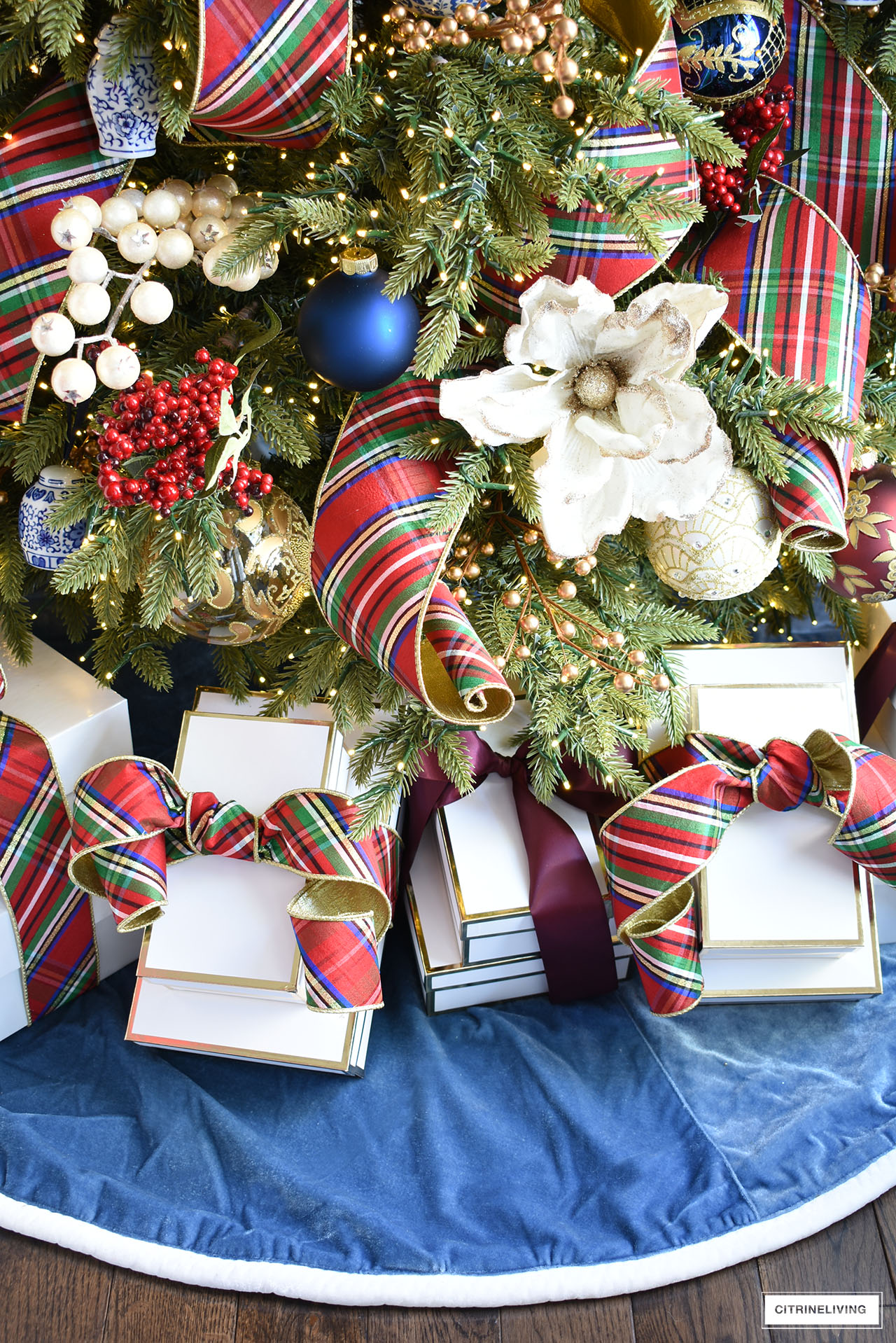 Christmas tree, velvet blue tree skirt, white gift boxes.