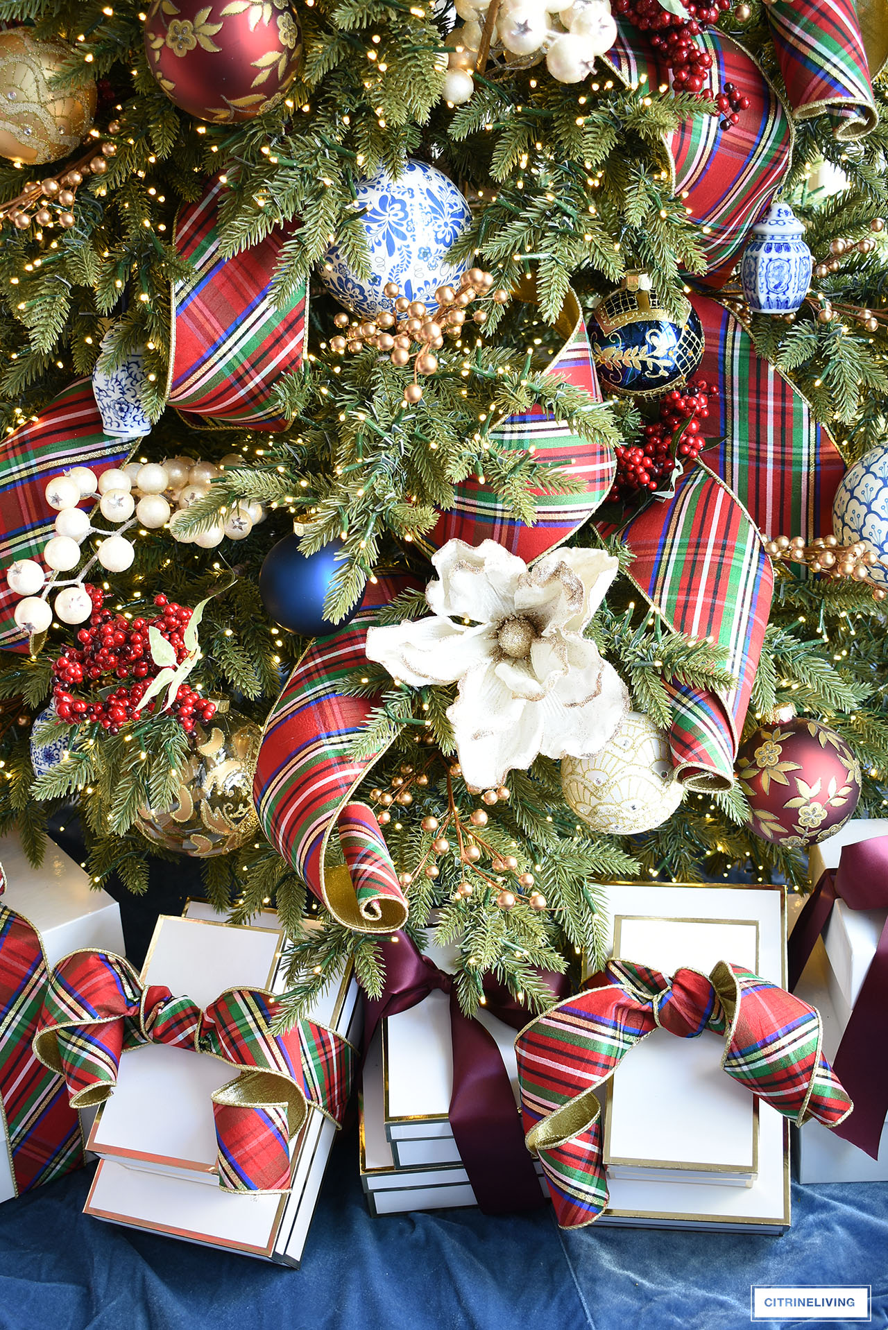 Christmas tree, velvet blue tree skirt, white gift boxes.