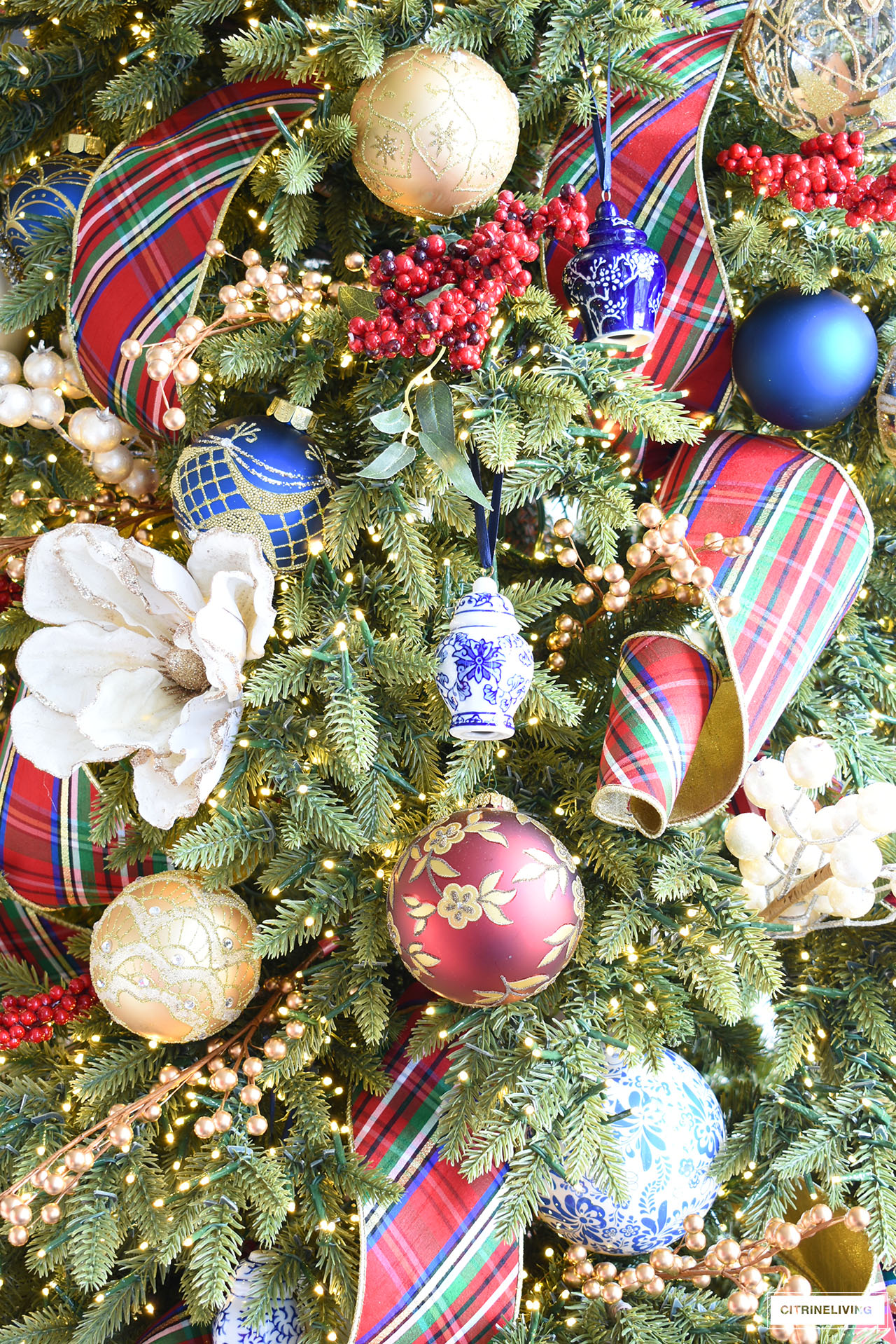 Christmas tree with red, gold and blue and white ornaments, red plaid ribbon