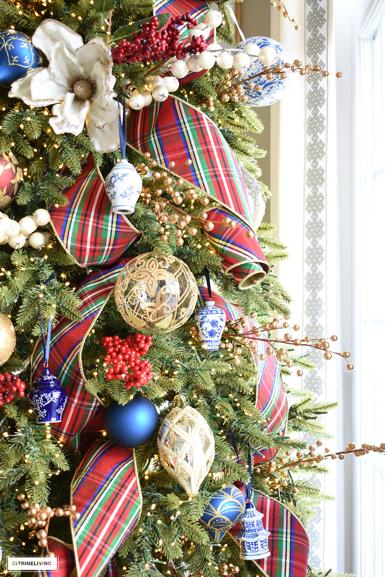 Christmas tree with blue and white ornaments, gold ornaments, red plaid ribbon