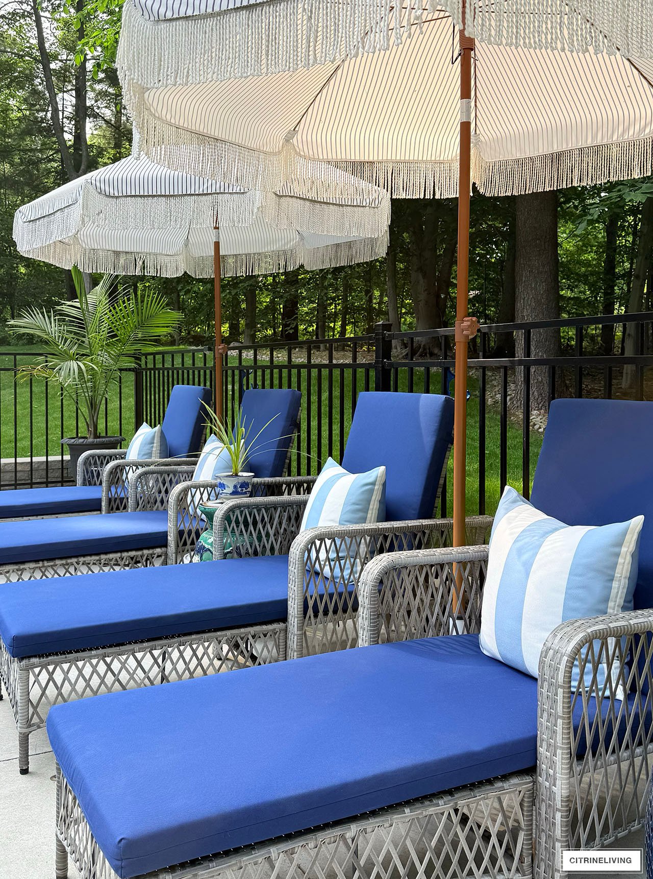 Pool loungers with navy cushions and striped throw pillows.